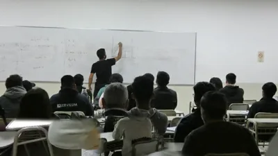 Juani resolviendo un ejercicio en el pizarrón mientras el curso lo sigue
